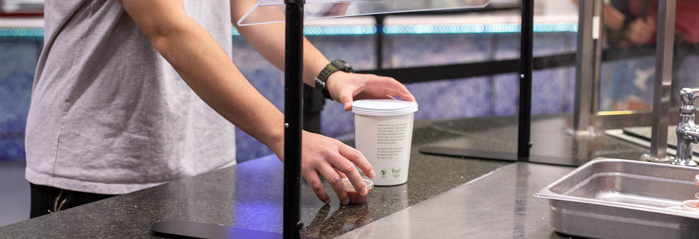 A student picks up a to-go container from a counter at Southside Cafe.