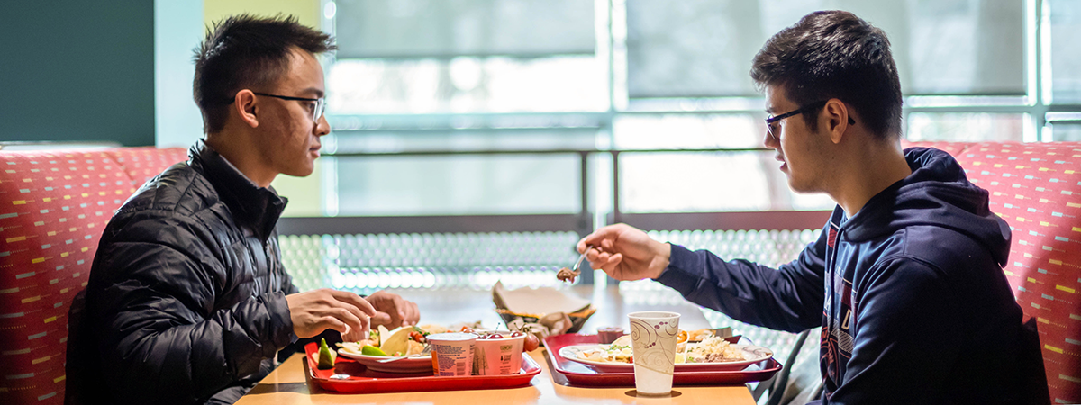 Two boys sitting at a table eating.