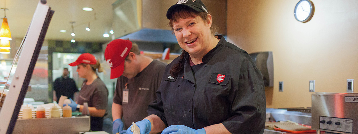 Women smiling while making a sandwich.