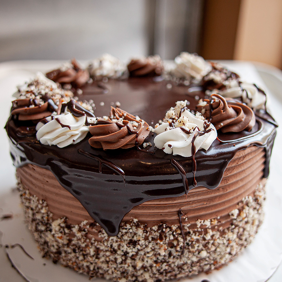 A whole chocolate cake with chocolate frosting and decorated with dripping chocolate.