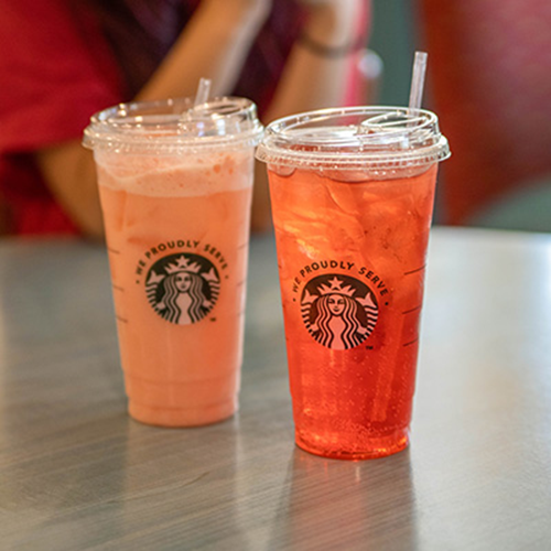 Pink and orange iced drinks in clear Starbucks cups.