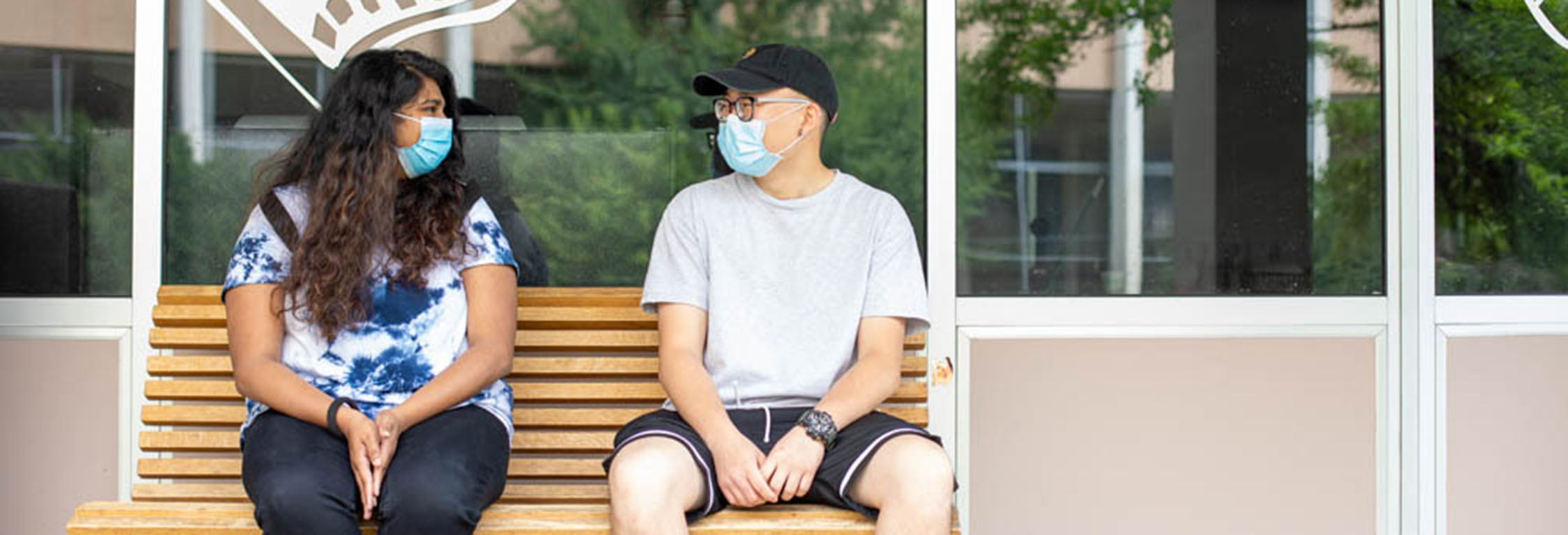 Two students wearing masks sit outside Flix Cafe.