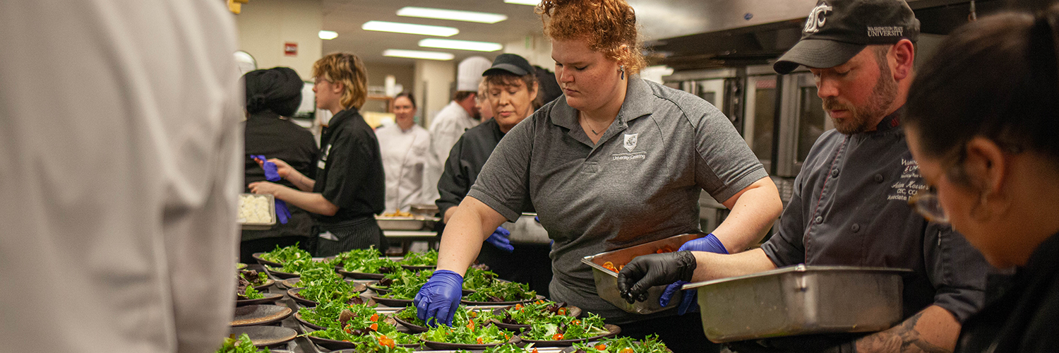 A number of employees preparing salads for a catering event.