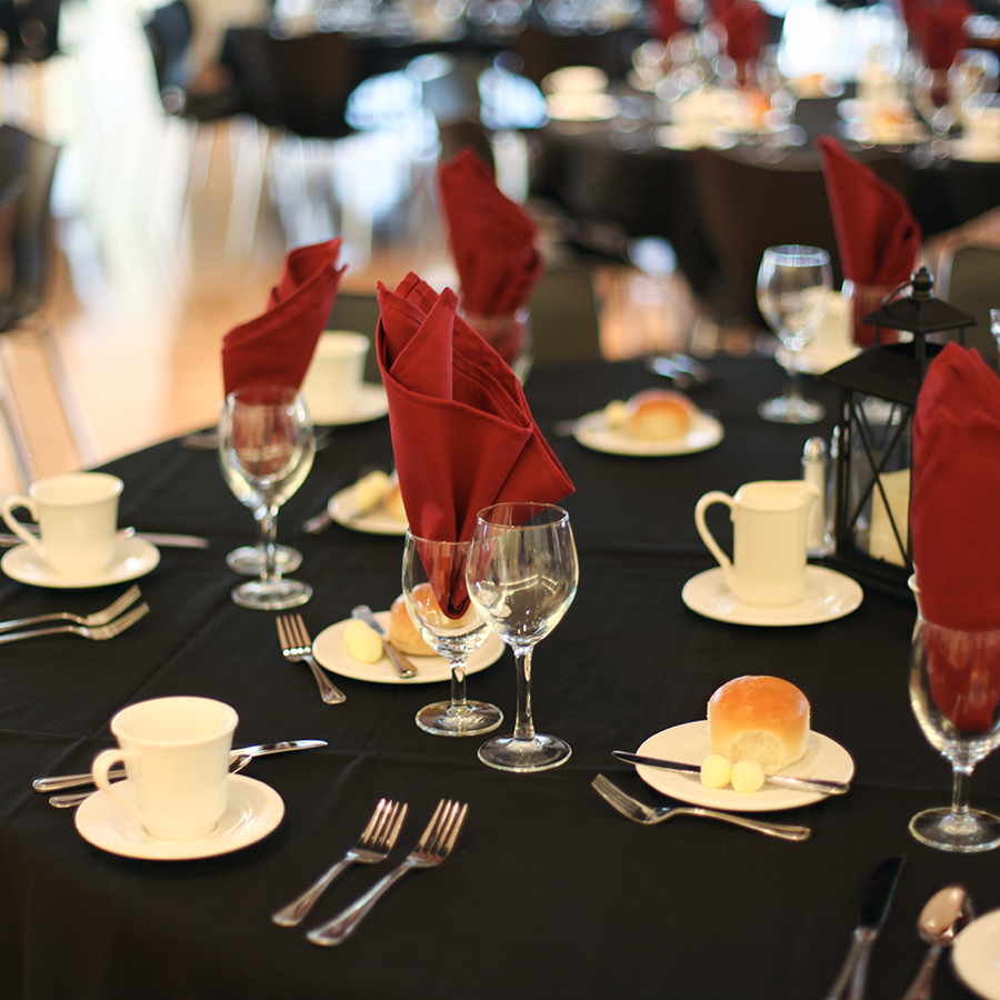 A table setting with a black tablecloth and red napkins.