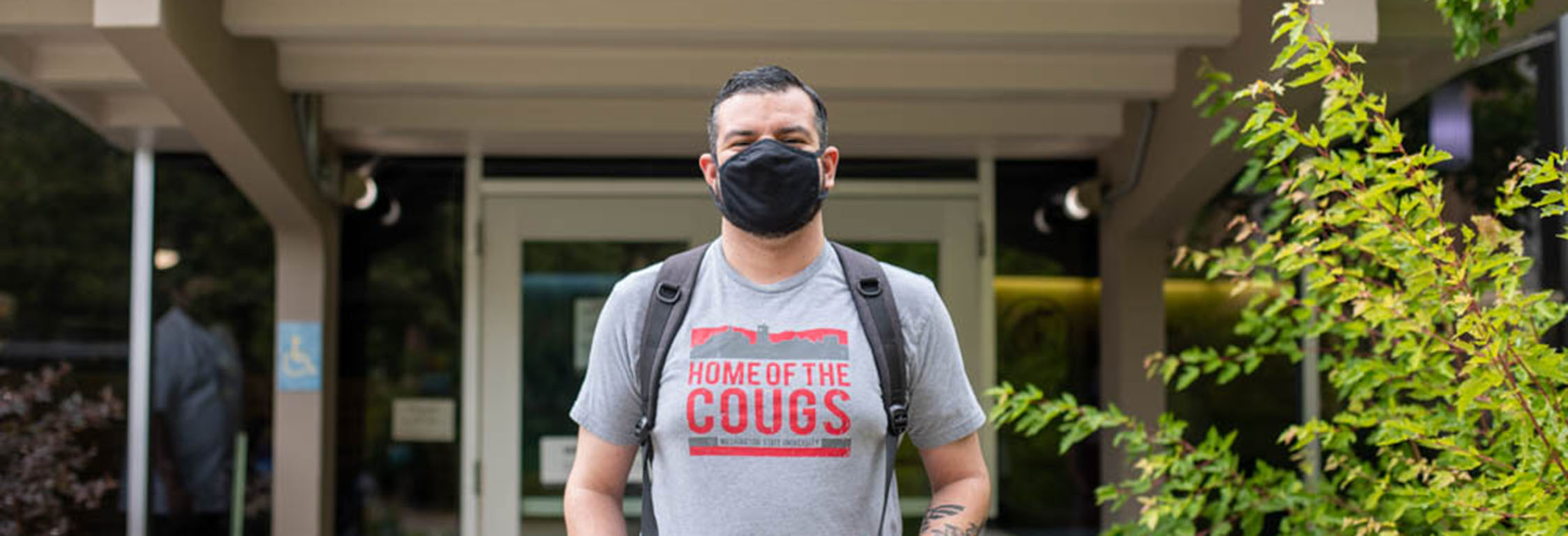 A student wearing a mask & a WSU t-shirt stands outside Southside Cafe.