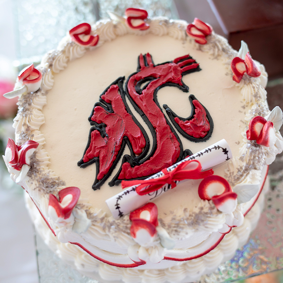 A WSU grad cake with white frosting a red WSU cougar.